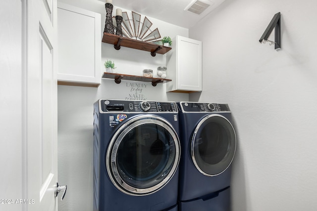 clothes washing area featuring cabinets and washer and dryer