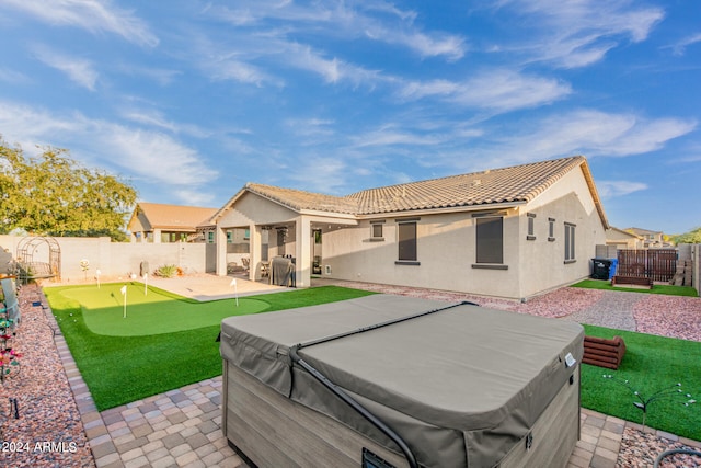 rear view of house featuring a hot tub and a patio