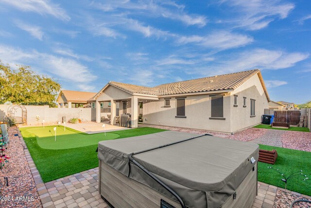 rear view of property featuring a fenced backyard, a patio, a hot tub, and stucco siding