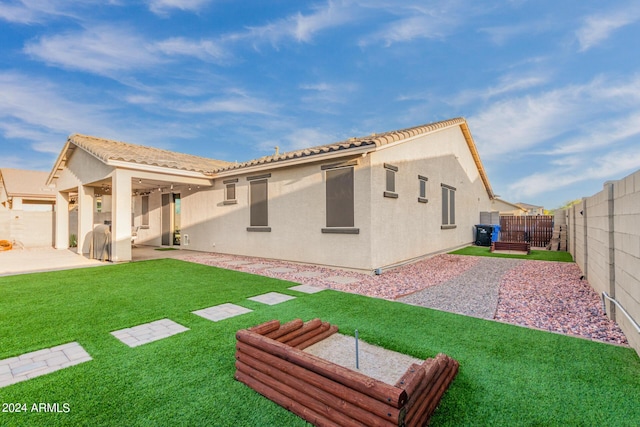 rear view of house featuring a tile roof, a patio, stucco siding, a lawn, and a fenced backyard