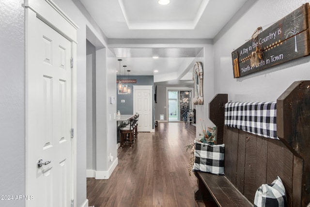 hallway with dark wood-type flooring and a raised ceiling