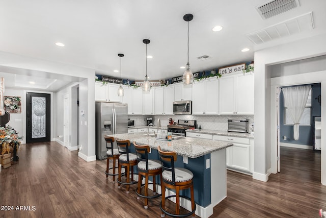 kitchen featuring a center island with sink, backsplash, appliances with stainless steel finishes, and dark hardwood / wood-style flooring