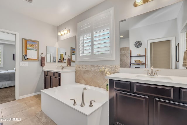 4229 W Magdalena Ln, Laveen, AZ 85339 - ensuite bathroom featuring tile patterned flooring, baseboards, a bath, two vanities, and a sink