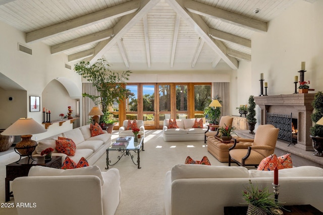 living room featuring visible vents, beamed ceiling, carpet floors, a warm lit fireplace, and high vaulted ceiling