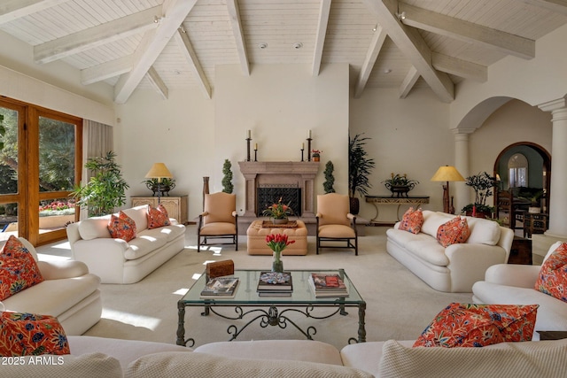 living room featuring a fireplace with raised hearth, carpet, wooden ceiling, arched walkways, and ornate columns