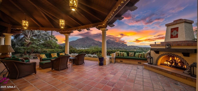 view of patio with an outdoor living space with a fireplace and a mountain view