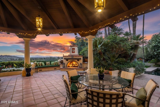 view of patio / terrace with a gazebo and a warm lit fireplace