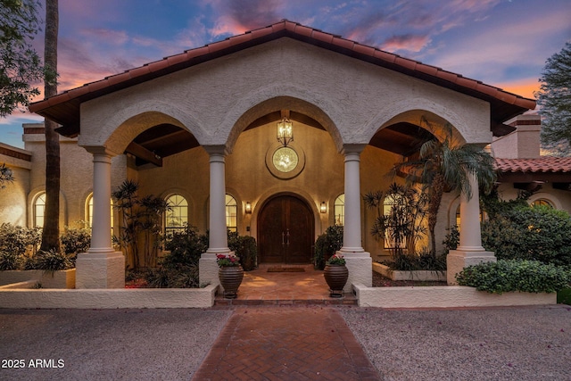 mediterranean / spanish home featuring stucco siding and a tiled roof