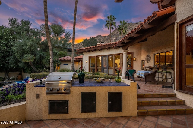 patio terrace at dusk featuring grilling area and area for grilling