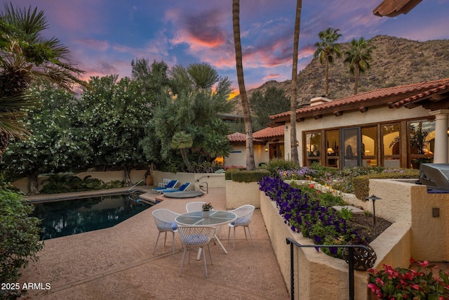 pool at dusk featuring a patio area and a fenced in pool