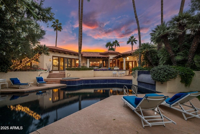 pool at dusk featuring a patio area and an outdoor pool