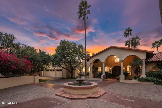 rear view of property featuring stucco siding, driveway, and a tiled roof