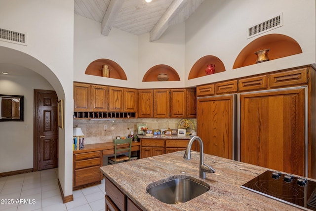 kitchen with visible vents, decorative backsplash, brown cabinetry, black electric cooktop, and a sink