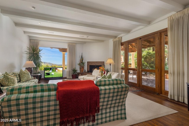 living room with beam ceiling, a fireplace, and wood finished floors