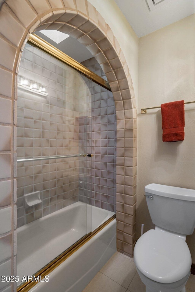 full bathroom featuring tile patterned floors, toilet, and bath / shower combo with glass door