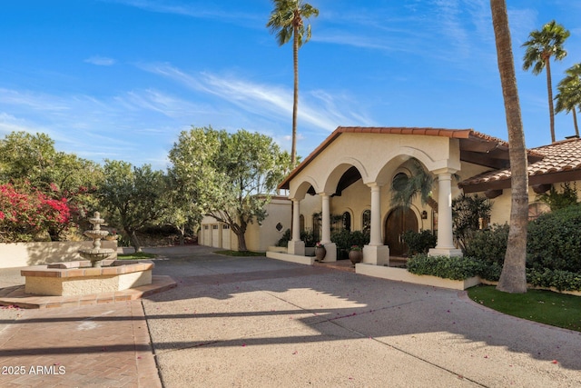 view of front facade featuring stucco siding, driveway, and a tile roof