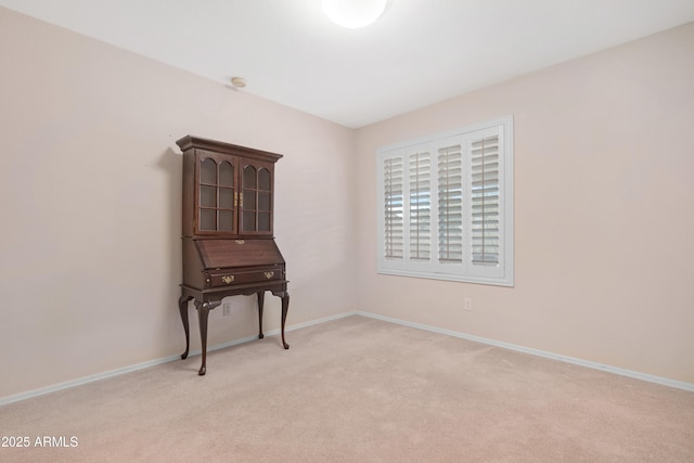 unfurnished room with baseboards and light carpet