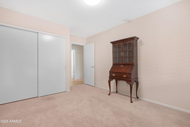 bedroom with light carpet, a closet, and baseboards