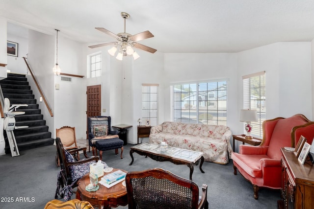 living room with ceiling fan, carpet flooring, and a high ceiling