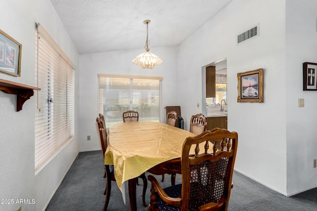 carpeted dining room with sink, a textured ceiling, and a chandelier