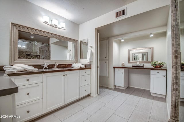 bathroom featuring vanity, a textured ceiling, and a tile shower