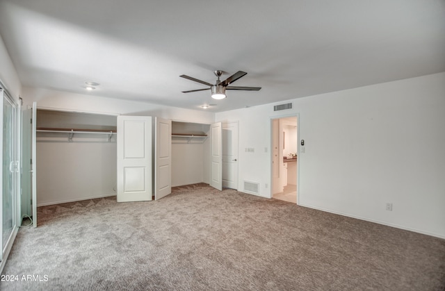 unfurnished bedroom featuring two closets, ceiling fan, and light carpet