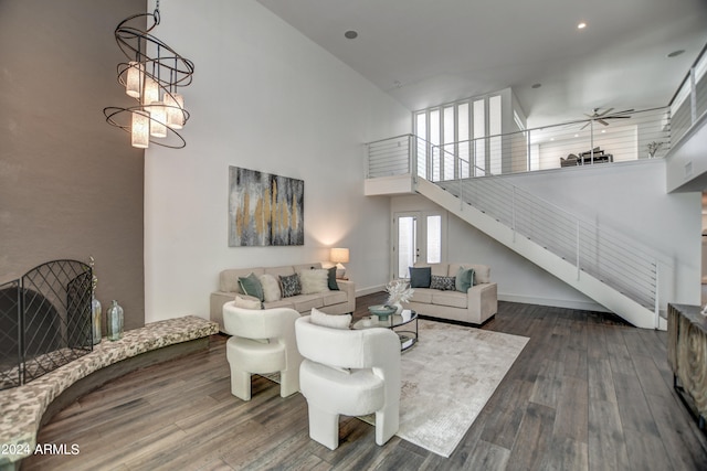 living room featuring dark wood-type flooring, a high ceiling, and ceiling fan with notable chandelier