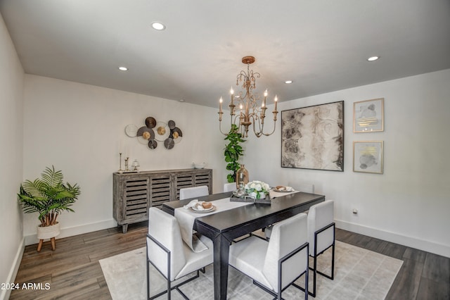 dining space with dark wood-type flooring and an inviting chandelier