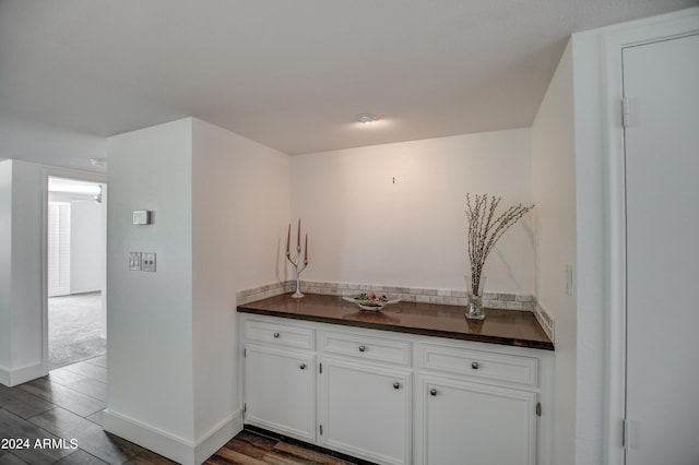 bar featuring dark hardwood / wood-style floors and white cabinets