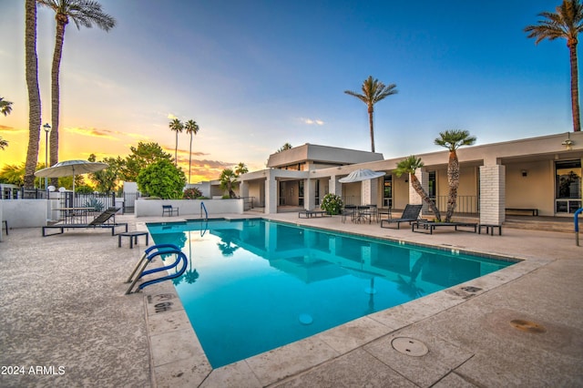 pool at dusk featuring a patio