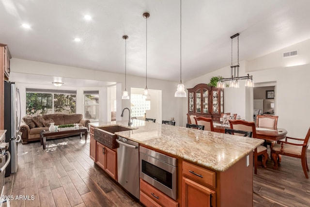 kitchen featuring appliances with stainless steel finishes, sink, an island with sink, and hanging light fixtures