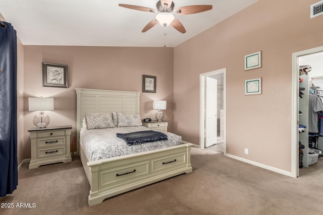 carpeted bedroom featuring ceiling fan, vaulted ceiling, ensuite bathroom, a walk in closet, and a closet