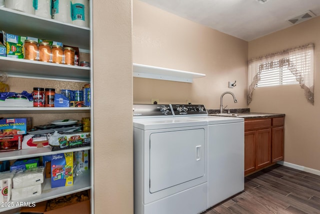 laundry area with cabinets, sink, washing machine and clothes dryer, and dark hardwood / wood-style flooring