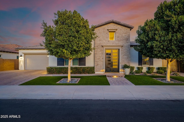 view of front of home featuring decorative driveway, brick siding, stucco siding, fence, and a garage