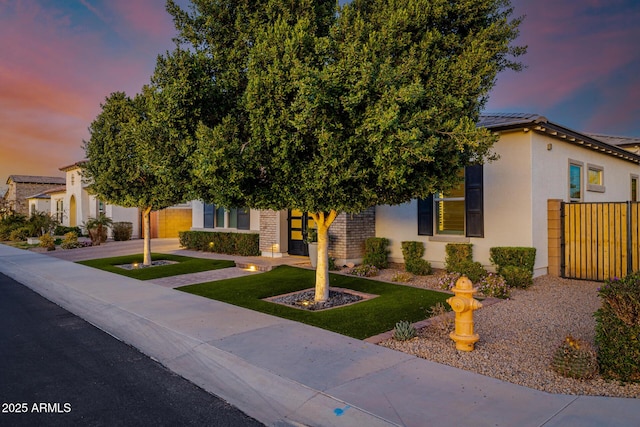 view of property hidden behind natural elements featuring fence and stucco siding