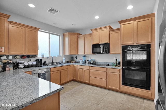 kitchen with light tile patterned flooring, light brown cabinetry, sink, light stone counters, and black appliances