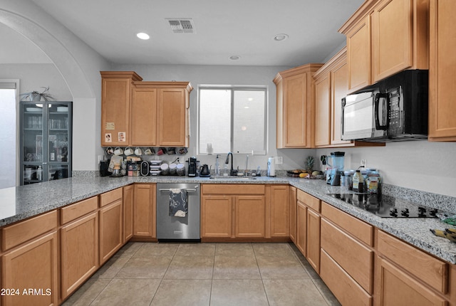 kitchen with light tile patterned flooring, black appliances, sink, light stone counters, and kitchen peninsula