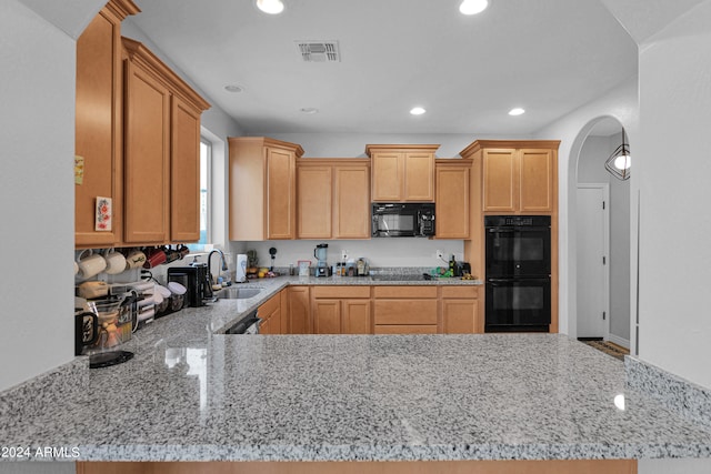 kitchen with sink, light stone counters, black appliances, light brown cabinetry, and kitchen peninsula