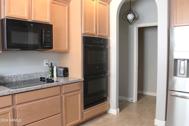 kitchen featuring light tile patterned flooring, light brown cabinetry, light stone counters, pendant lighting, and black appliances