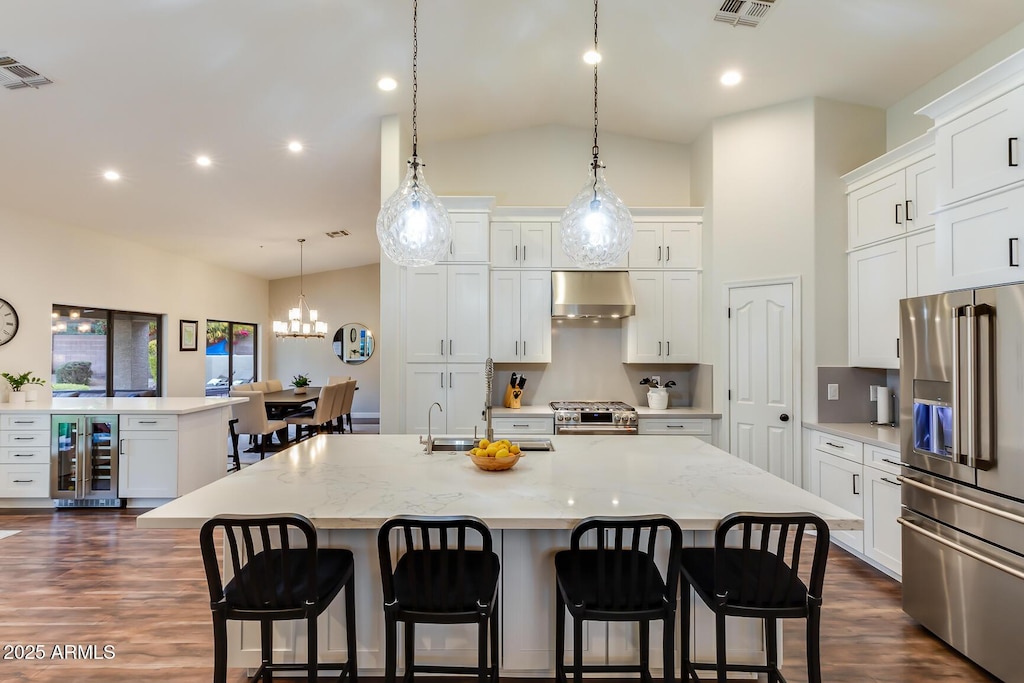 kitchen featuring a large island, range hood, premium appliances, white cabinets, and beverage cooler