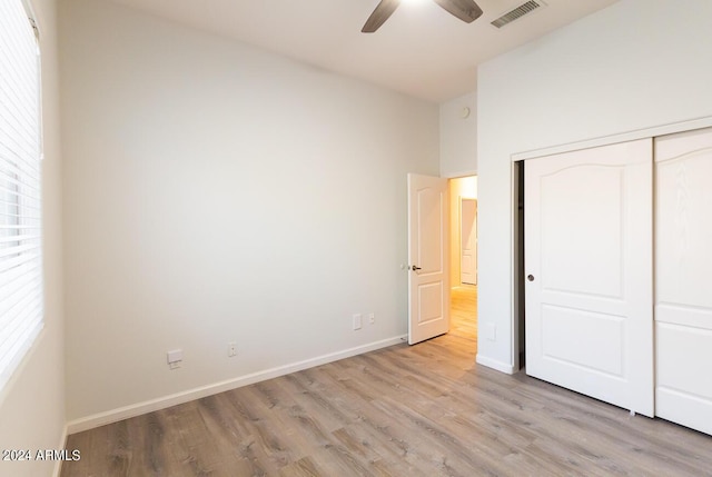 unfurnished bedroom with ceiling fan, light wood-type flooring, and a closet