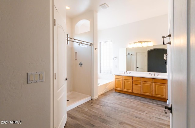 bathroom with plus walk in shower, wood-type flooring, and vanity