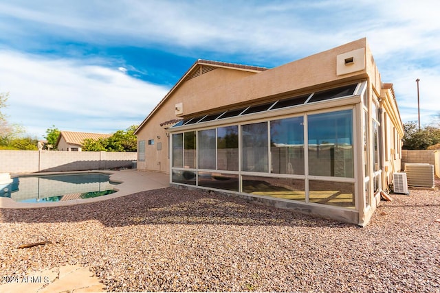 back of house with central AC unit, a fenced in pool, and a patio