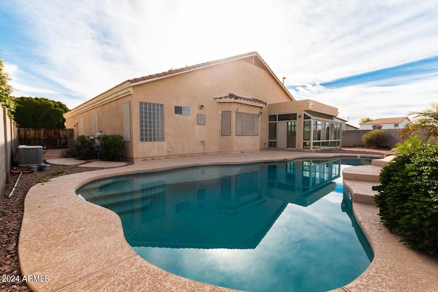 view of pool with cooling unit and a sunroom