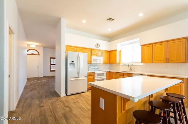 kitchen featuring a breakfast bar, a kitchen island, white appliances, and backsplash