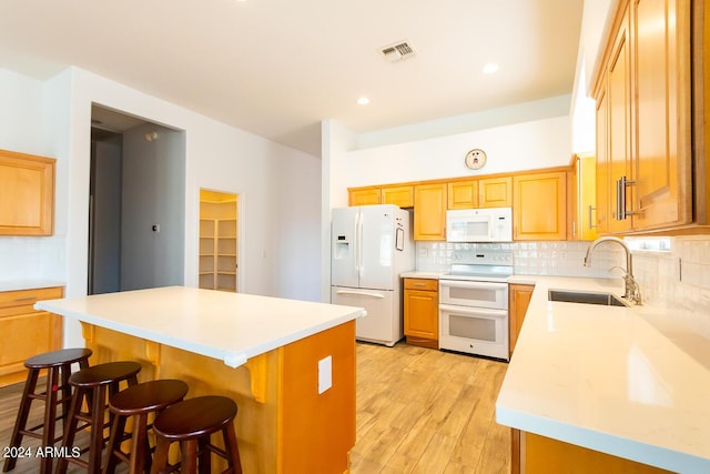 kitchen with sink, tasteful backsplash, white appliances, a breakfast bar area, and a kitchen island