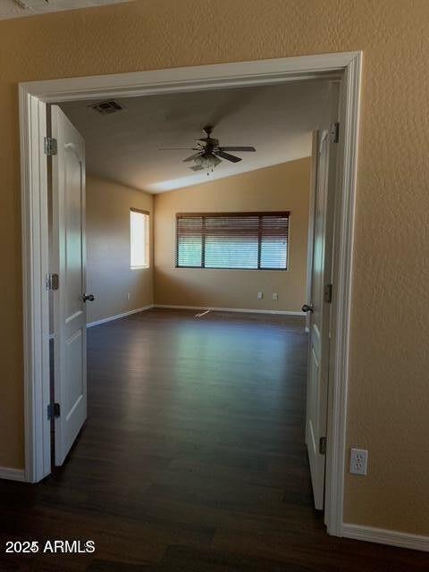 unfurnished room with baseboards, ceiling fan, visible vents, and dark wood-style flooring