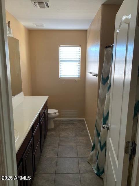 bathroom with toilet, vanity, baseboards, visible vents, and tile patterned floors