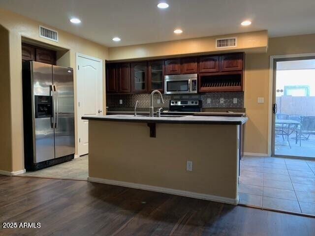 kitchen featuring a center island with sink, visible vents, stainless steel appliances, and a sink