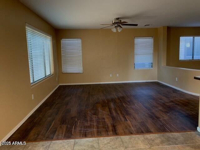 spare room with wood finished floors, a ceiling fan, and baseboards